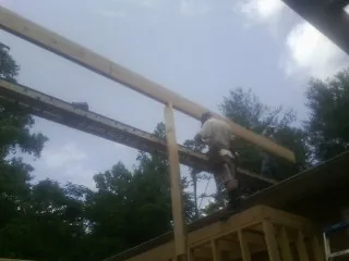 Carpenter setting a ridge beam over a new addition frame — Ice Dam Removal by Roofing Brothers in Leota