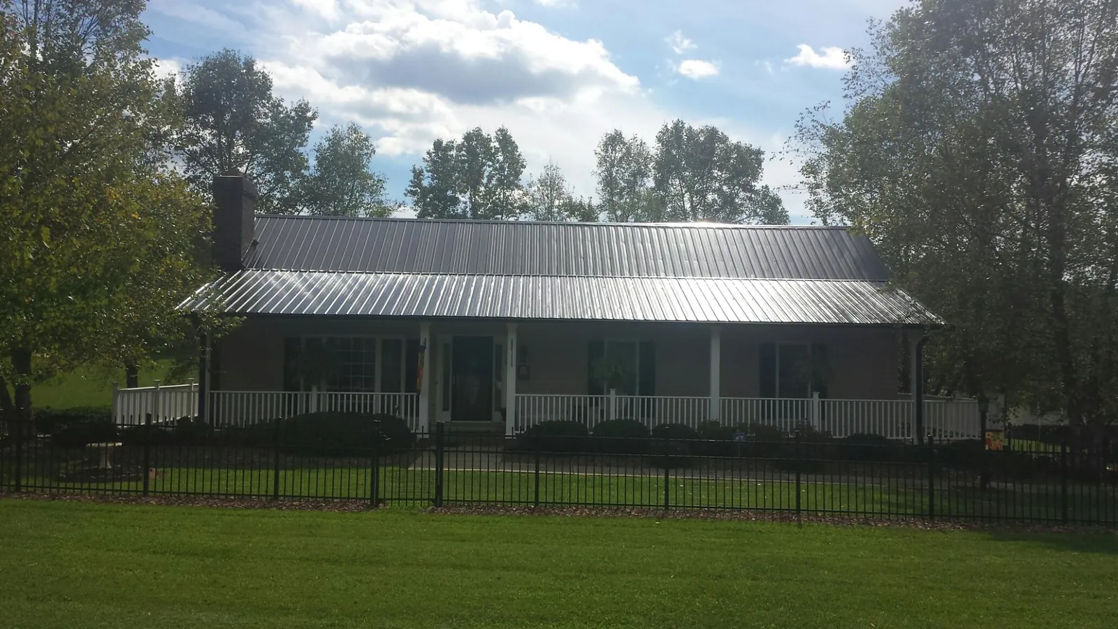 Gray metal roof on a brick ranch with a full width front porch — Gutter Guard Installation work by our crew in Leota