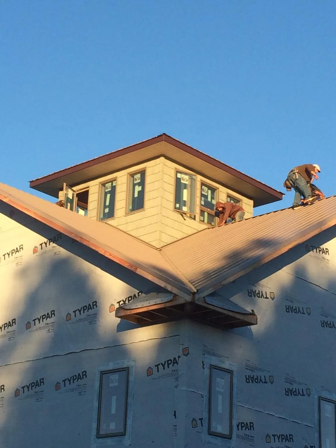 Roofers working around a rooftop cupola on a new metal roof at sunset — Roof Waterproofing in Leota by Roofing Brothers